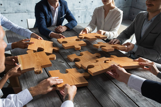 Settlement-Conferences People with large wood puzzle pieces